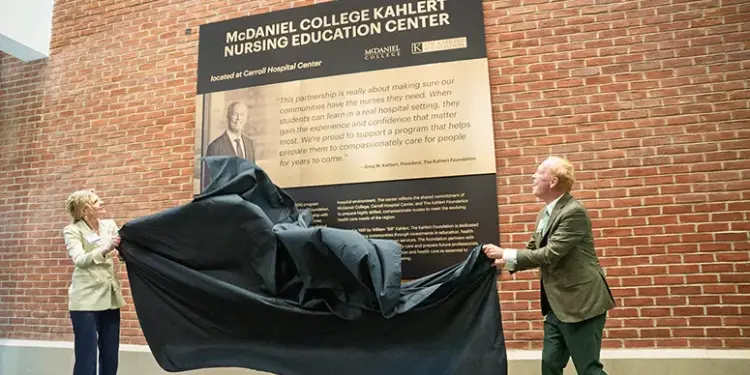 mcdaniel-college-kahlert - Carroll News | Carroll Publications | Carroll County, MD Two people unveil a plaque for the McDaniel College Kahler Nursing Education Center against a brick wall outside a hospital setting.