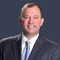 Cawley_FeaturedImage - Carroll News | Carroll Publications | Carroll County, MD - Carroll News | Carroll Publications | Carroll County, MD Smiling man in a dark suit and light blue tie against a dark blue background.