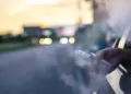 Person vaping from a car window at sunset, with vapor plume filling the air outside the vehicle.