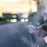 Person vaping from a car window at sunset, with vapor plume filling the air outside the vehicle.
