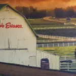 tablecloth_bob-evans - Carroll News | Carroll Publications | Carroll County, MD White barn with a green roof labeled 'Bob Evans' in a fenced rural farm landscape.
