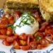 Plate of chopped cherry tomatoes around a burrata ball, topped with basil, with toasted bread slices on a blue-and-white patterned plate.