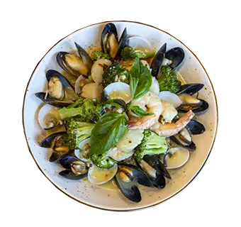 Bowl of seafood pasta with mussels, clams, shrimp, lemon wedges, and fresh basil.
