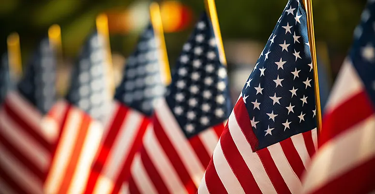Rows of American flags on flagpoles, close-up foreground flag with others blurred in the background at a patriotic display